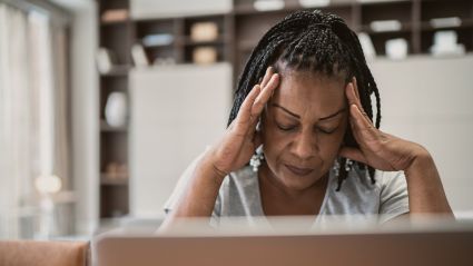 woman at a computer with hands on her temples