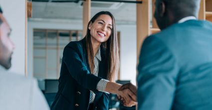 A woman and man shake hands in a business meeting.