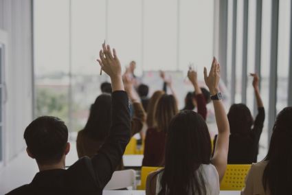 A picture of a group of people raising their hands after a presentation