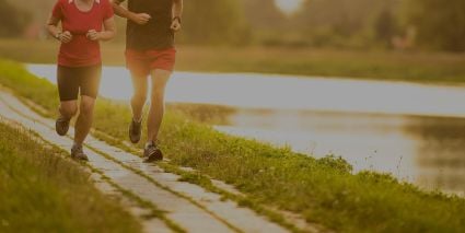 Two people running on a path by a lake