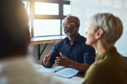 Three people sit at a table to have a conversation