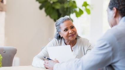 woman looking at another person holding a paper