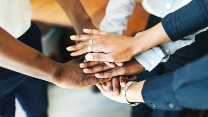 Three people with their hands stacked on top of one another.