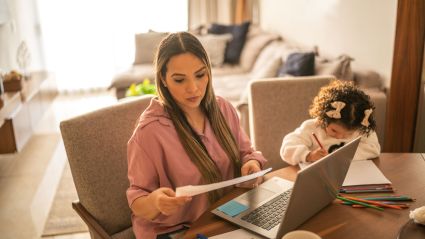 parent at laptop with child on side writing something and looking down