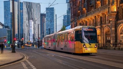 An image of a Piccadilly line tram moving through a London street with both modern and old city buildings in the background. The image prefaces an article titled "Increased Regional Investment is the Key to British Economic Mobility"