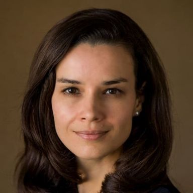 A smiling light-skinned female with brown hair against a brown background