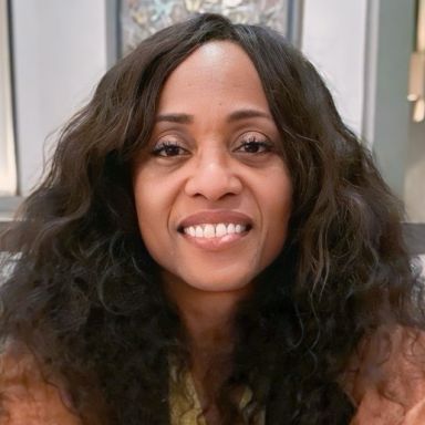 headshot of person smiling with dark wavy hair parted to the side