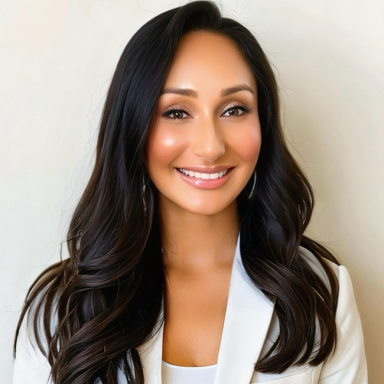 A smiling light-skinned, female-presenting individual with dark brown hair and dark eyes. She is wearing a white blazer.