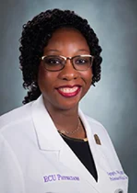 A smiling darker-skinned female with black curly hair wearing glasses and a lab coat against a light gray backgroundt