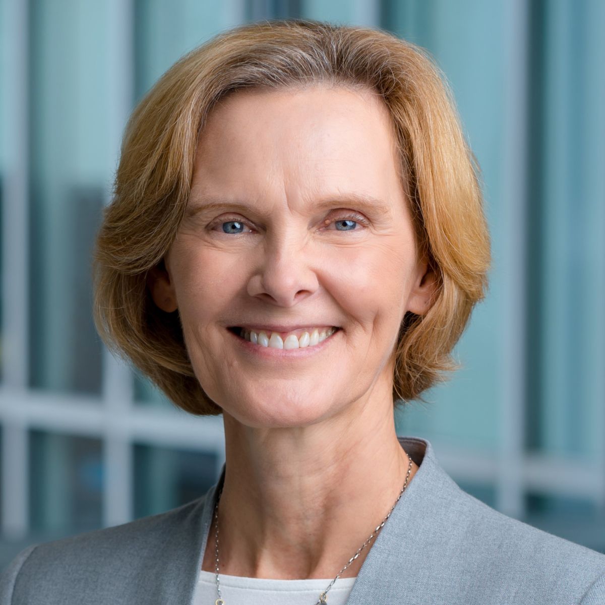 Professional smiling woman against a glass backdrop. 