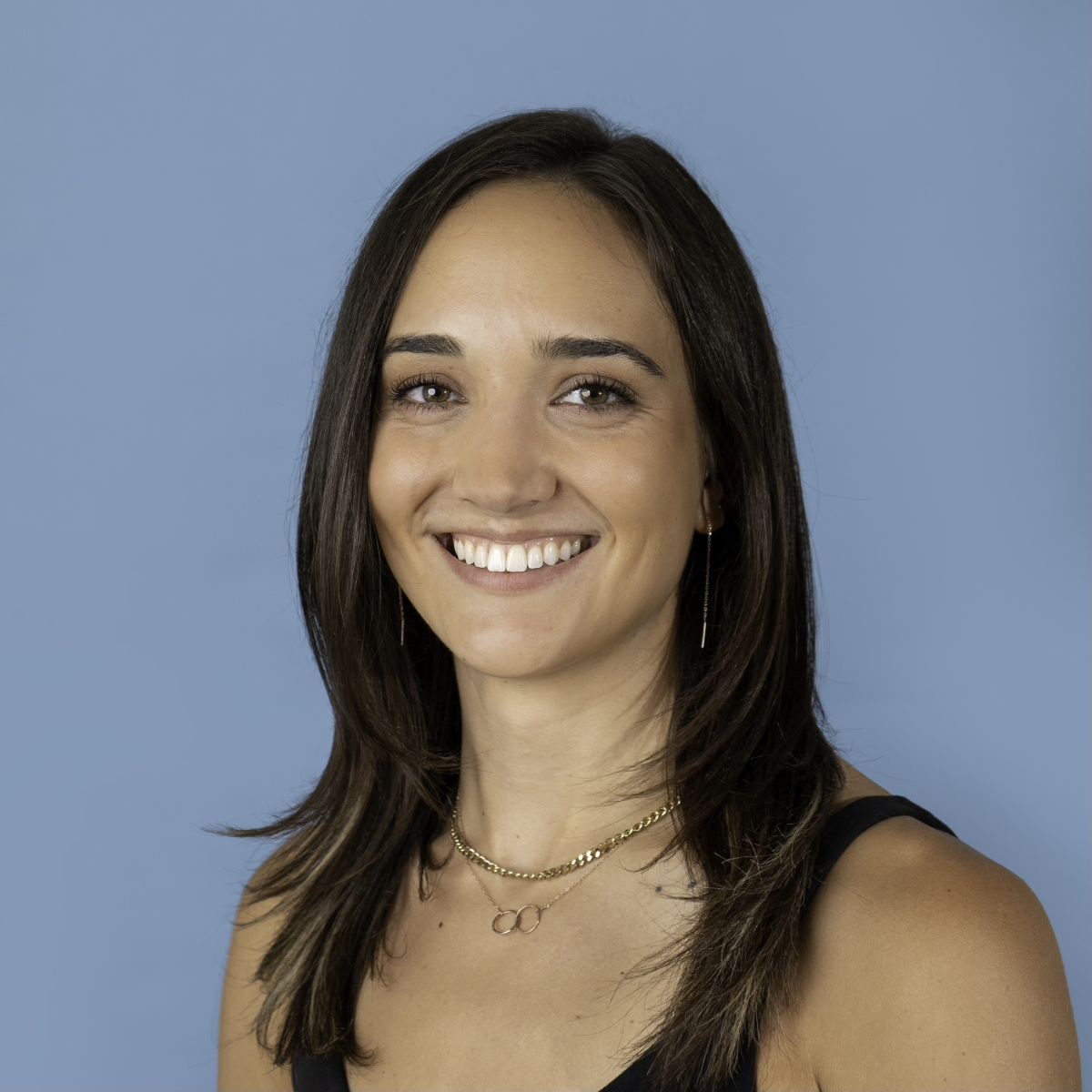 A smiling light-skinned female with long brown hair against a light blue background