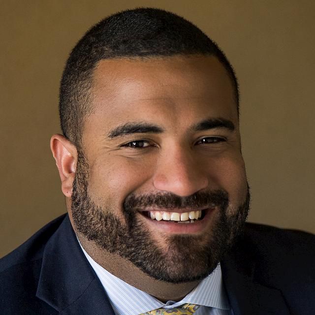 headshot of person with close shaved dark hair, beard, smiling