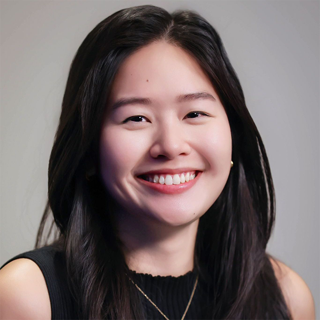 A headshot of a smiling adult woman named Alina Sin, who is  an associate director on the Business and Program Development team within the International pillar at the Milken Institute. She has light white skin, black hair, a black shirt, and is Asian in appearance.