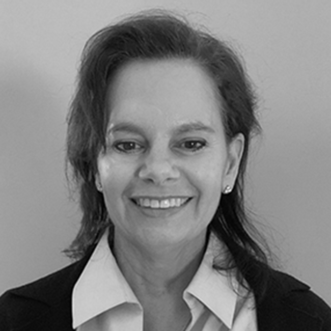 An image of a smiling adult woman named Kim Batarse, who is  a director on the Business and Program development team at the Milken Institute. The image is black and white and she has shoulder-length seemingly brunette hair, white skin, and is wearing a white collared shirt. 