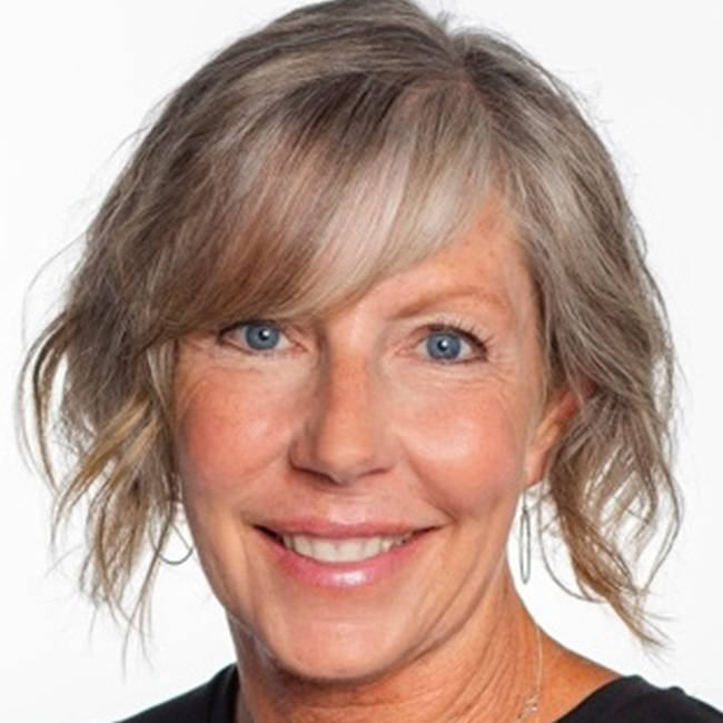 An image of a smiling adult woman named Lisa Covington, who is a director of project management for the Business and Program Development team at the Milken Institute. She has bobbed gray and blonde hair, white skin, and blue eyes.