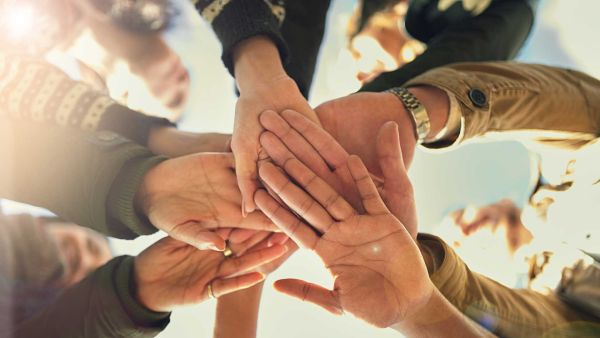 Multiple hands touching in a circle on a sunny day