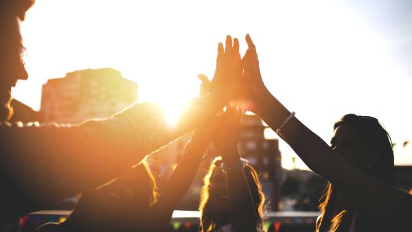 Four people raise their hands in a high five