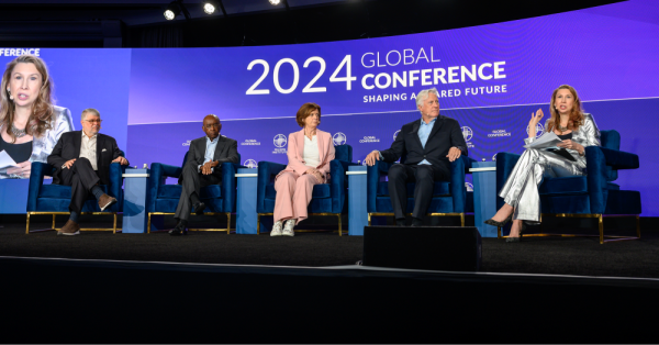 Five panelists sit on stage during an event for a discussion