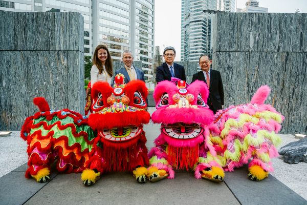 Four people stand behind Chinese dragon statues