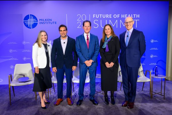 An image of five adults standing in front of a "2024 Future of Health Summit" backdrop from the Milken Institute. There are two women and three men, and they are all wearing business attire. 