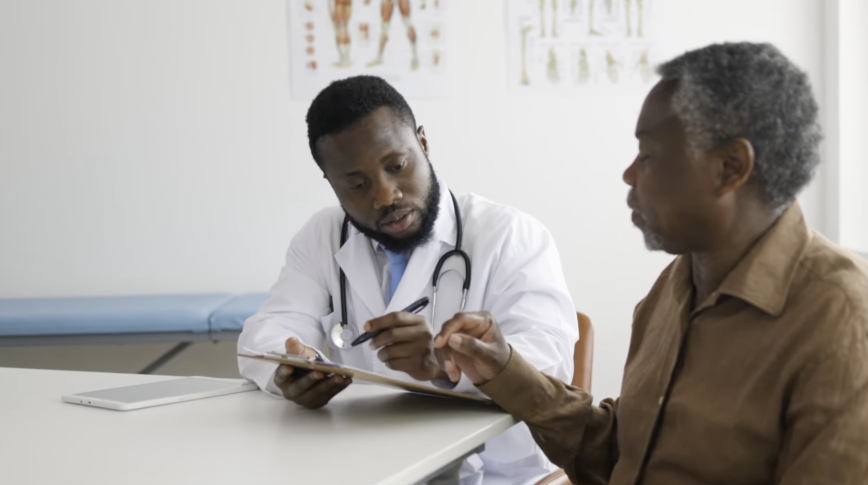 A doctor with a clipboard having a discussion with an elderly patient