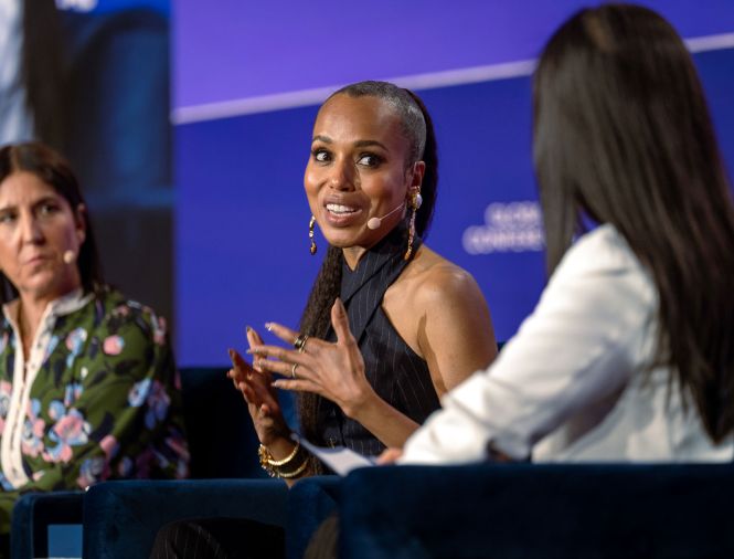 An image of speakers from The Milken Institute's Global Conference 2024 that is being used in preparation of Global Conference 2024. There are three women speakers, discussing a "Solving Challenges" panel. One woman has tanned white skin and short black hair, and she is looking at the middle speaker with a serious expression. The middle speaker is a woman with light brown skin and brown hair, and she is actively speaking. The third speaker has long black hair and is also facing the middle speaker.