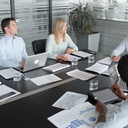 group of office workers seated at a conference table talking