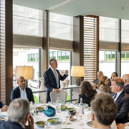 A group of people sitting at tables listen to a speaker