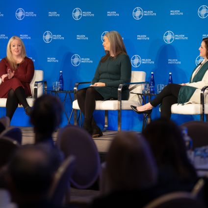 A group of three people sit on stage to have a discussion during an event