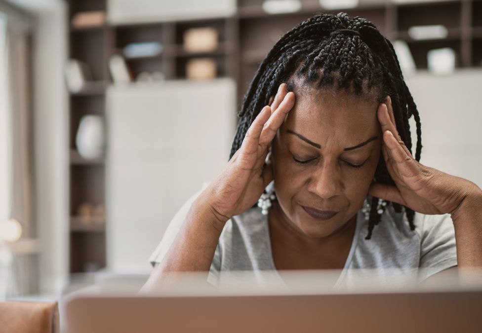 woman at a computer with hands on her temples