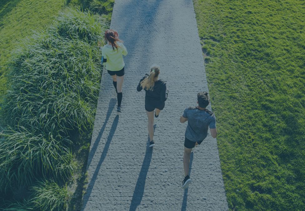 three people jogging on a paved trail