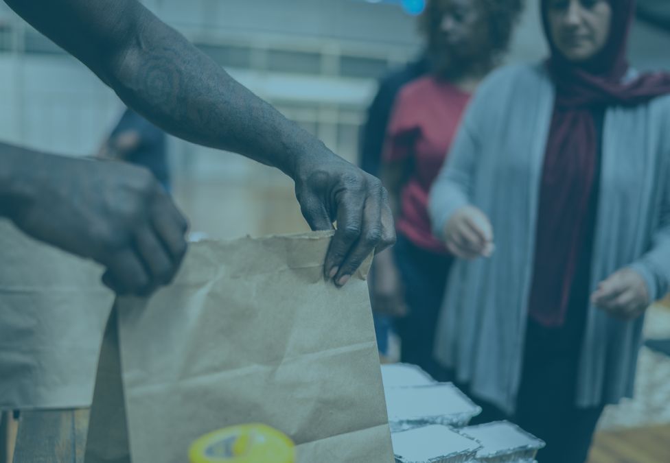 Man handing a food parcel to a woman