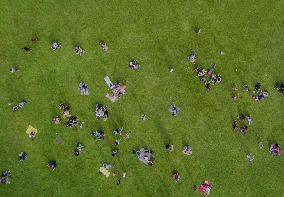 An aerial shot of a crowd of people on a green lawn