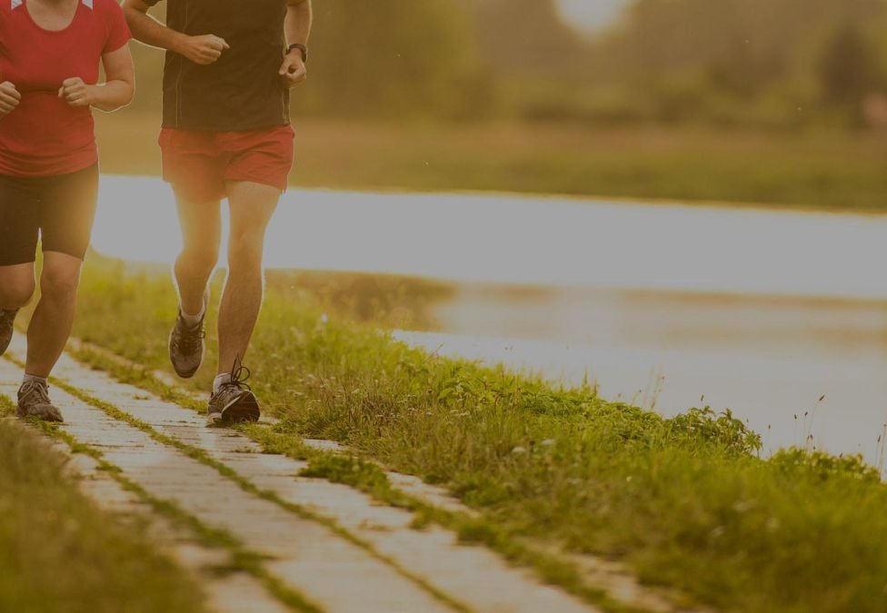 Two people running on a path by a lake