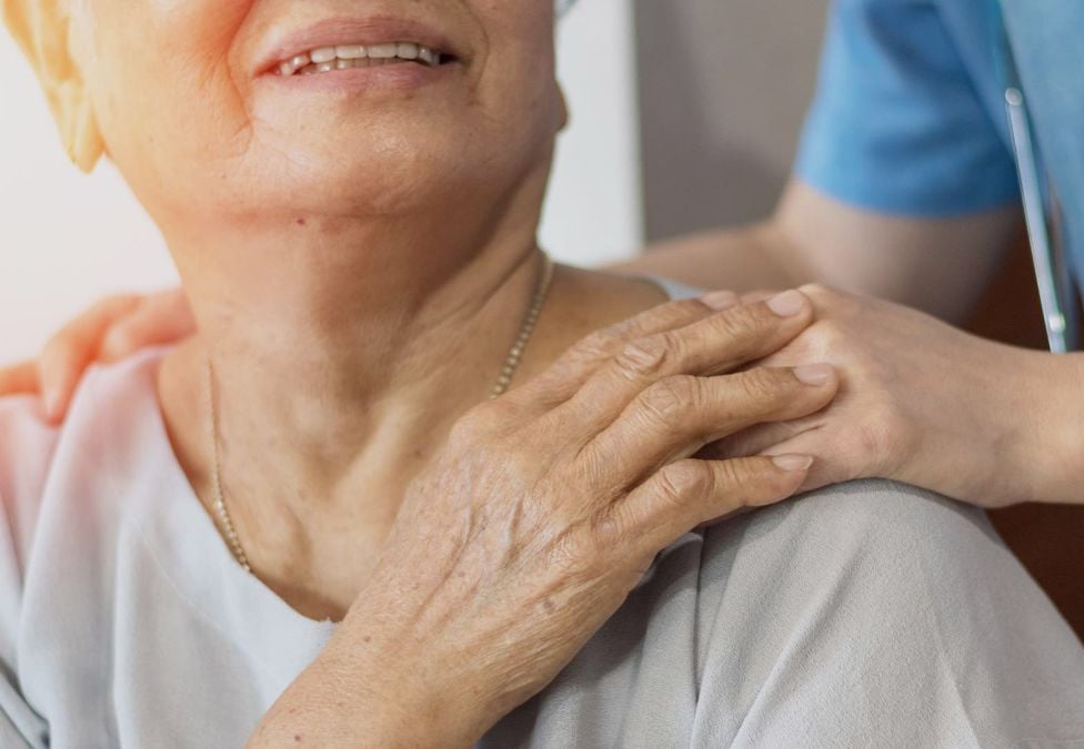 A caregiver puts their hands on a patient's shoulder