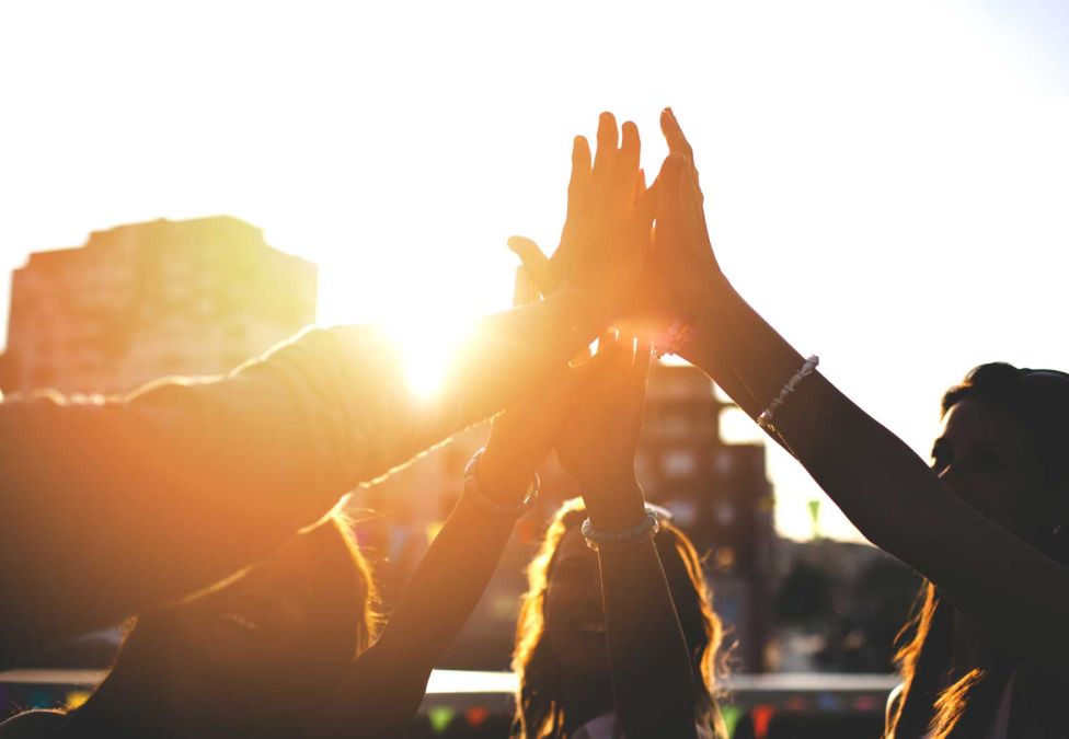 Four people raise their hands in a high five