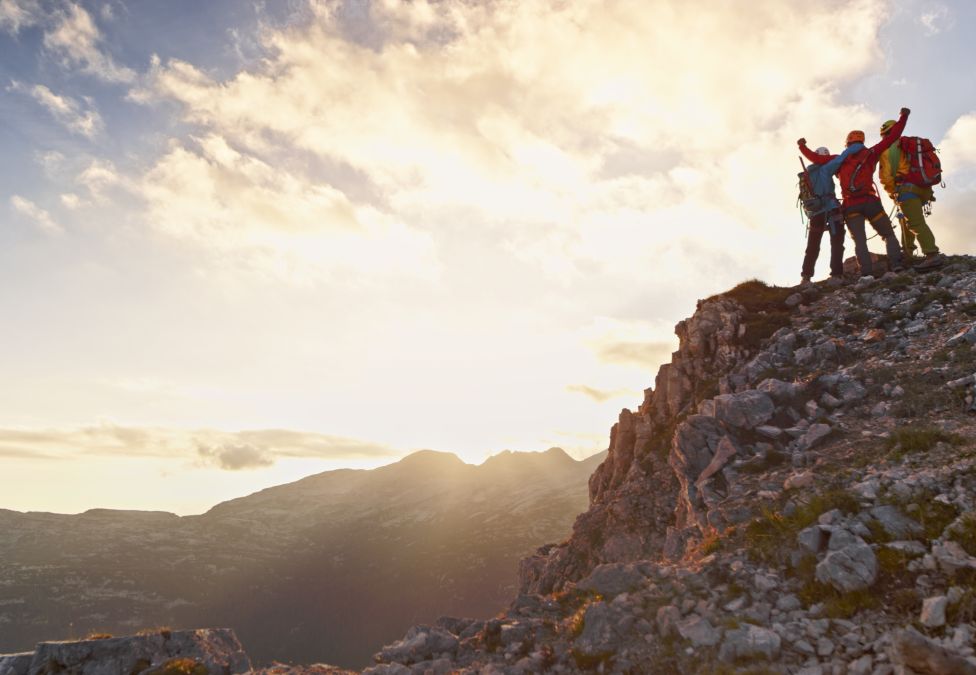 People stand on top of a mountain at sunset