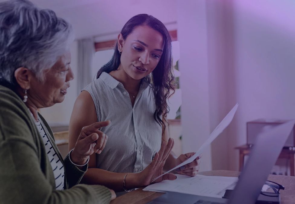 An older woman speaks to her doctor in front of a laptop.