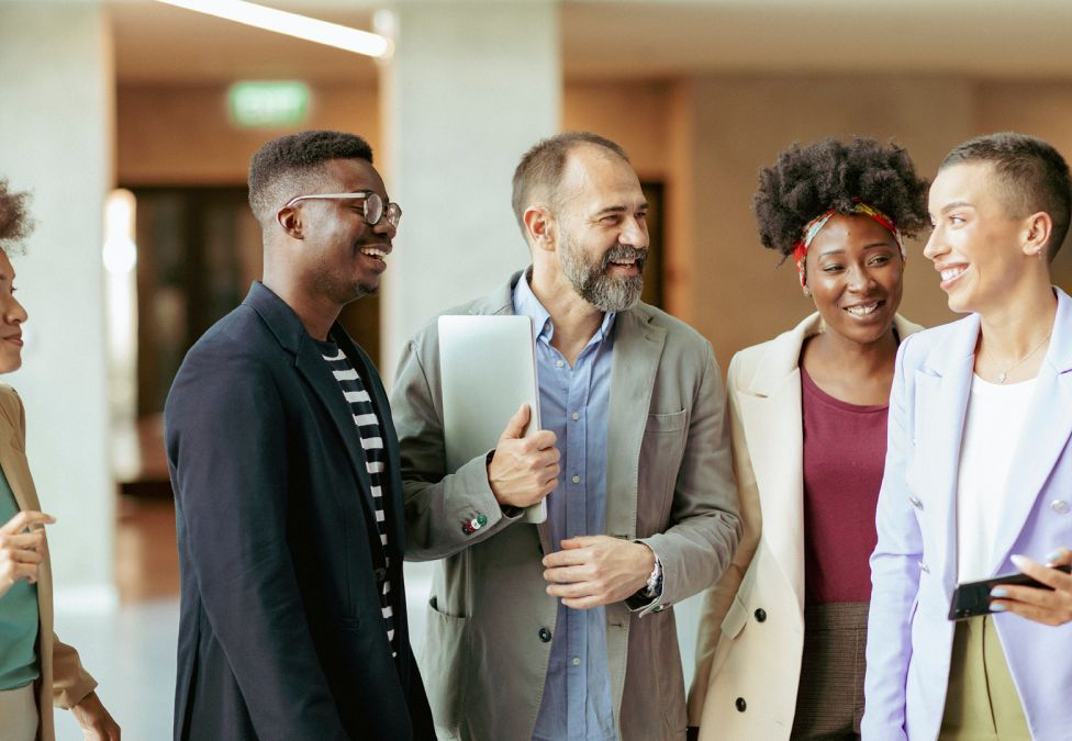 A group of people in an office setting laugh and talk