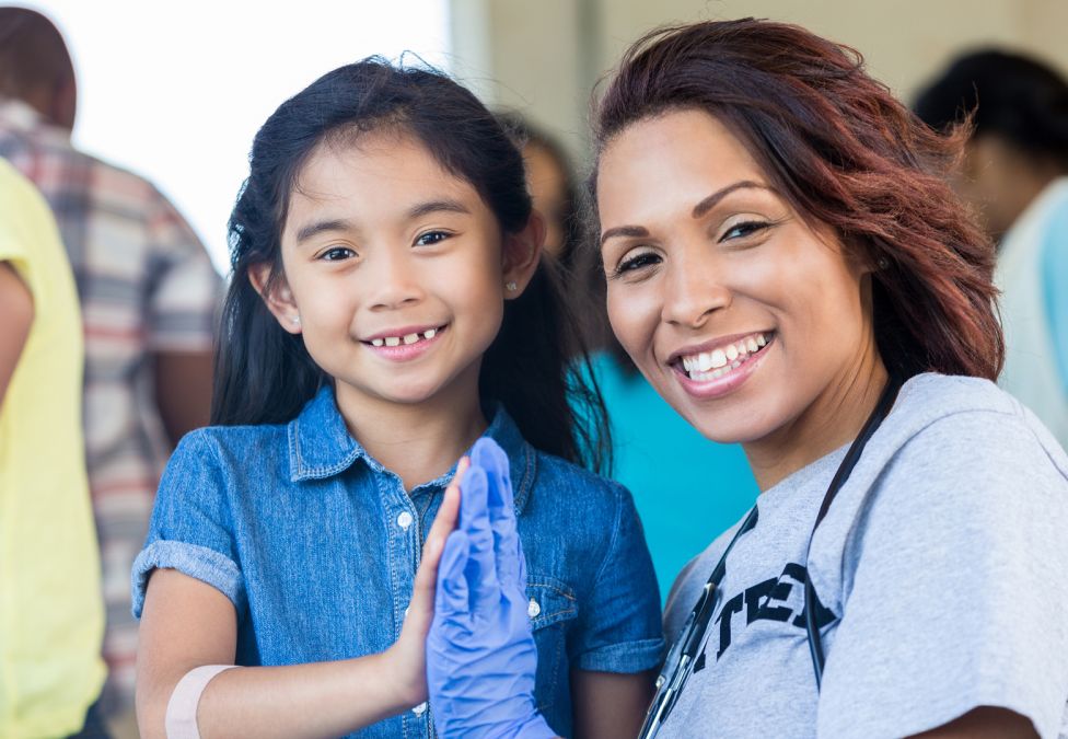 A young girl and a woman place their palms together.