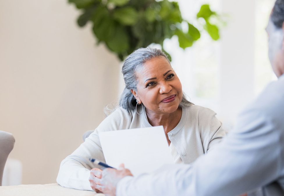 woman looking at another person holding a paper