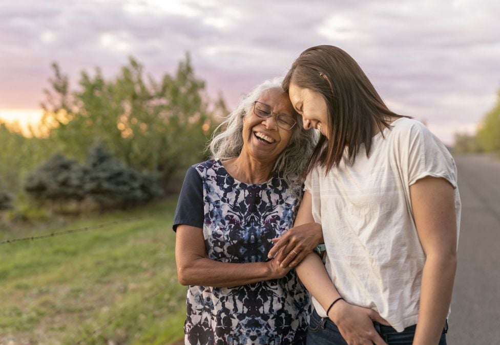 two women leaning on each other on a walk