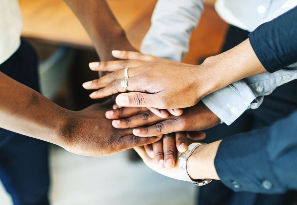 Three people with their hands stacked on top of one another.