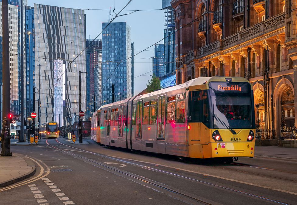 An image of a Piccadilly line tram moving through a London street with both modern and old city buildings in the background. The image prefaces an article titled "Increased Regional Investment is the Key to British Economic Mobility"